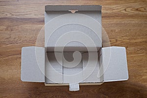 Top view from above of open empty brown cardboard box on wooden background.