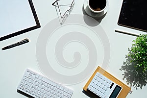 Top view above of white office desk table with keyboard computer, notebook and coffee cup with equipment other office