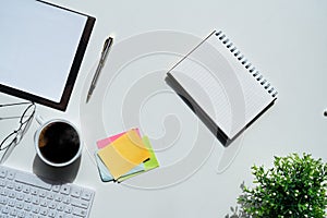 Top view above of white office desk table with keyboard computer, notebook and coffee cup with equipment other office