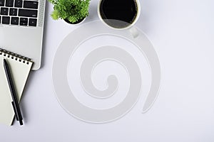 Top view above of White office desk table with keyboard of laptop, notebook and coffee cup