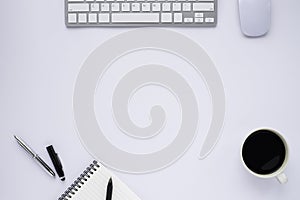 Top view above of White office desk table with keyboard, notebook and coffee cup with equipment other office supplies.