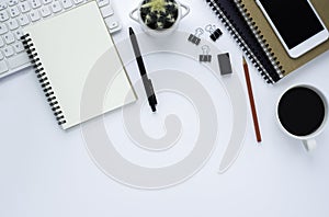 Top view above of White office desk table with keyboard, notebook and coffee cup with equipment other office supplies.