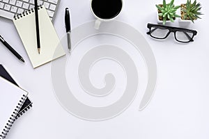 Top view above of White office desk table with keyboard, notebook and glasses