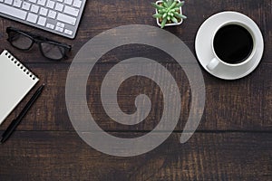 Top view above of Wooden office desk table with keyboard, notebook and coffee cup with equipment other office supplies. Business a