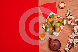 Top view accessories Chinese new year festival decorations.orange,leaf,wood basket,red packet,plum blossom on red background.