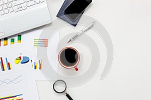 Top view accessories office desk concept.mobile phone,coffee,notepaper,pen,laptop,eyeglasses,chart on white office desk with copy