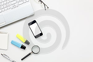 Top view accessories office desk concept.mobile phone,notepaper,pen,laptop,eyeglasses on white office desk.