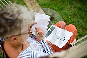 Top view of active senior woman working outdoors in garden, home office concept.