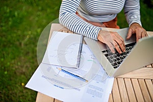 Top view of active senior woman working outdoors in garden, home office concept.