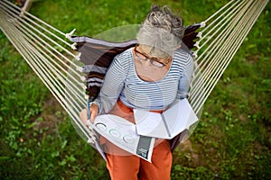 Top view of active senior woman working outdoors in garden, home office concept.