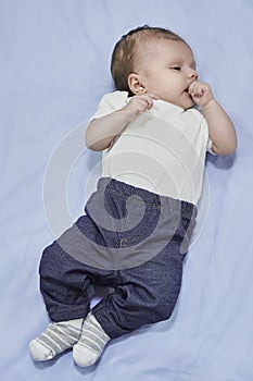 Top view of adorable baby lying on blue bedding