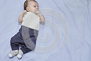 Top view of adorable baby lying on blue bedding