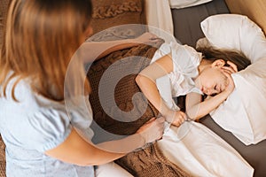 Top view of adorable sick little girl sleeping on bed in children room under blanket at home. Concept of children health