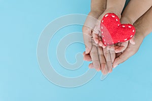 Top view of adult and child holding red heart in hands