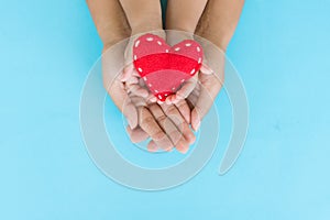 Top view of adult and child holding red heart in hands