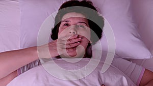 Top view. Adult Woman with red hair yawns in bed in the morning.