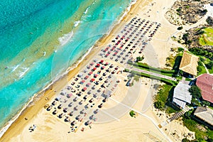 Top view aerial drone photo of Banana beach with beautiful turquoise water, sea waves and red umbrellas. Vacation travel