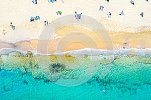 Top view aerial drone photo of beautiful beach with beautiful turquoise water, sea waves and people. Vacation travel background.