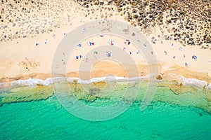 Top view aerial drone photo of beautiful beach with beautiful turquoise water, sea waves and people. Vacation travel background.