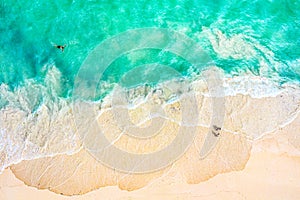 Top view aerial drone photo of ocean seashore with beautiful turquoise water, foam sea waves and people. Caribbean resort.