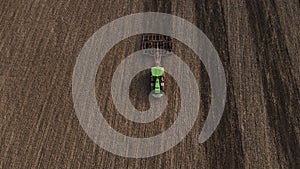 Top view or aerial drone view on green tractor plows the agricultural field. Agricultural concept. 4k resolution.