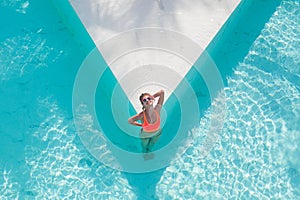 Top view aerial photo of model in bright swimwear relaxing in hotel pool during her summer weekend