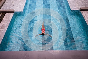 Top view aerial photo of a seductive model in white swimwear is enjoying relax in hotel pool during her summer