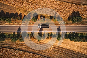 Top view aerial photo of truck on the road through plain landscape countryside