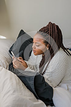 Top view African american female student dressed casually holding mobile phone and typing messages and communicating