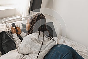 Top view African american female student dressed casually holding mobile phone and typing messages and communicating