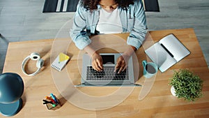 Top view of African American woman working with laptop indoors at home typing