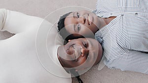 Top view of afro american couple black middle aged adult husband and ethnic wife lying together on floor looking at