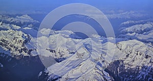 top view through airplane of mountain ranges with snow of switzerland, winter holidays