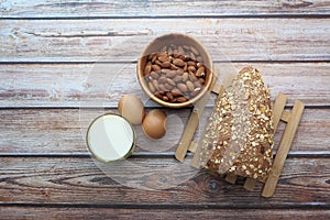 Top view of almond, eggs , milk and bread on table