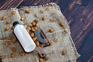 Top view of almond milk with sesame in a plastic bottle with almonds nut and sesame seeds on rustic fabric wooden tray and table.