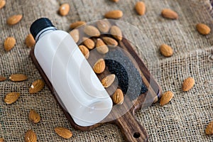 Top view of almond milk with sesame in a plastic bottle with almonds nut and sesame seeds on rustic fabric wooden tray and table.