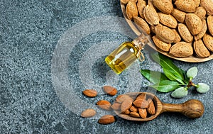 Top view Almond nuts and oil in wooden shovel, almonds with shell in bamboo bowl