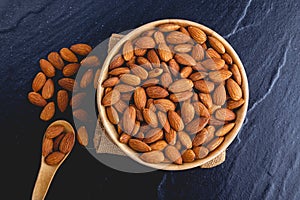Top view of almonds on dark stone table with wood photo