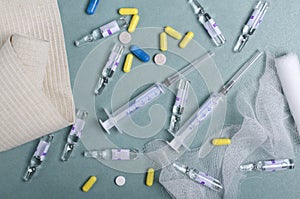 Top view of amploules, pills, capsules, syringes, bandages on the blue nurse`s table