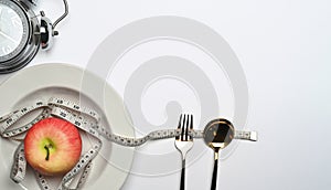 Top view apple, measure tape, spoon fork and alarm clock on white background with copy space for text.