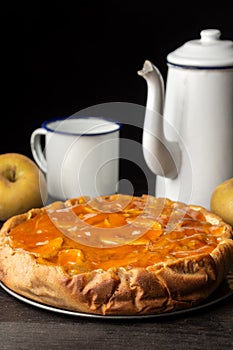 Top view of apple pie with cup and rustic coffee pot, selective focus, black background,