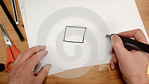 Top view, an architect`s hand draws the square base for a house, ideal footage for topics such as building renovation