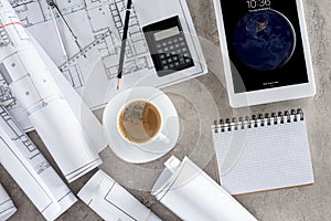 top view of architect workplace with coffee cup blueprints calculator and ipad tablet