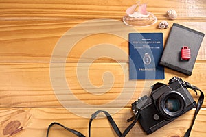 Top view of Argentine passport and travel accessories on table. Camera, wallet, miniature suitcase and embarkation, and seashells.