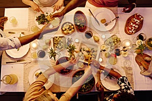 Top view of arms of intercultural family members sitting by served table