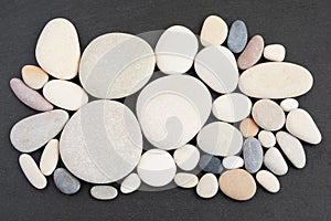 Top view of arranged pebble stones on black slate background