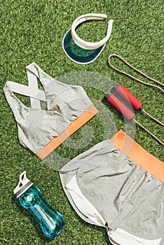 top view of arranged sportswear, water bottle, jump rope and cap