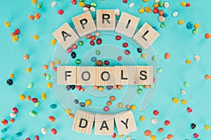 top view of arranged wooden cubes in april fools day lettering on blue surface with candies, 1 april holiday concept
