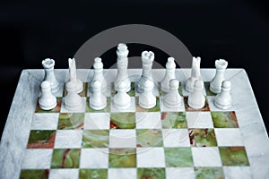 Top view of arrangement of white chess figures on marble green and white chess desk. Leadership in business is right start
