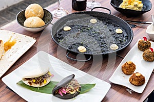 Top view of Arros negre and variety of delicious dishes and cutlery on a wooden restaurant table photo